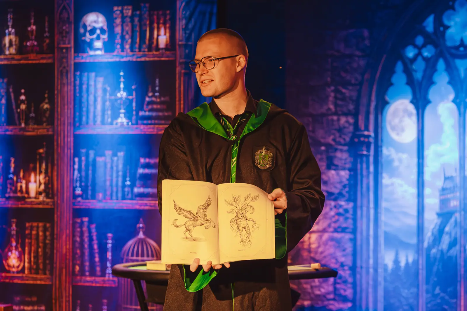 Iluzjonista prezentuje dzieciom księgę magicznych stworzeń podczas pokazu iluzji